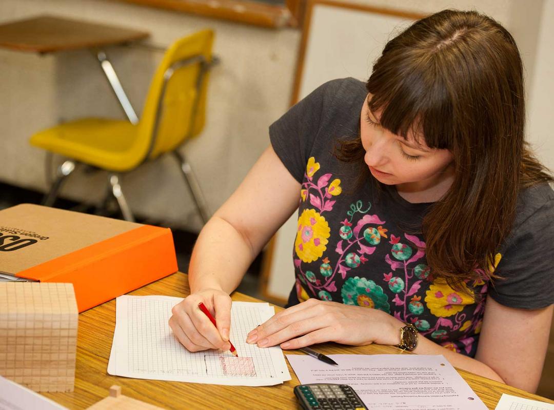 female student working on math on table