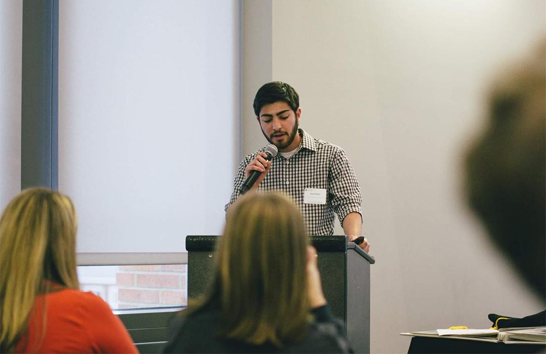 Tori Puoci speaking behind podium in lecture room