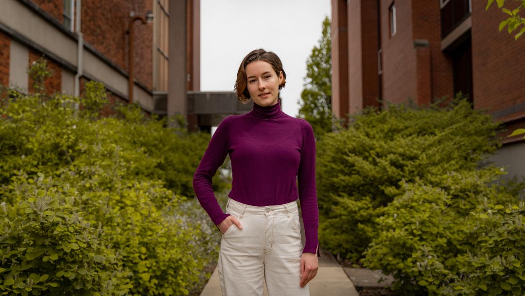 Elizaveta Zhivaya standing outside with green plants behind her.