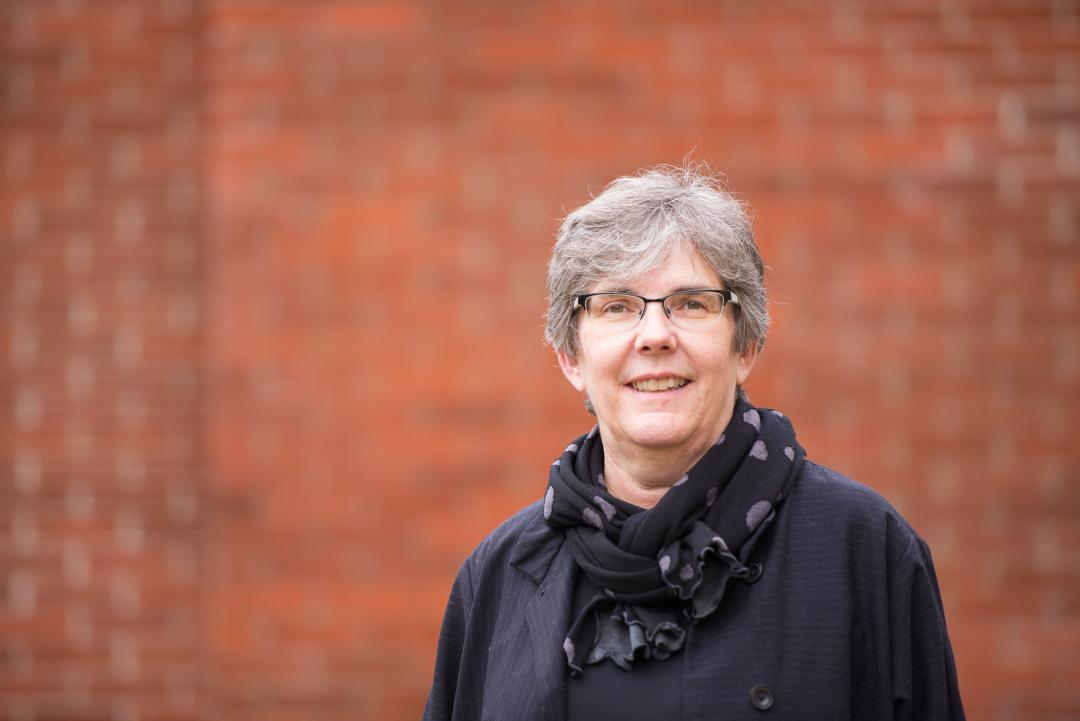 A woman in glasses standing in front of a brick wall
