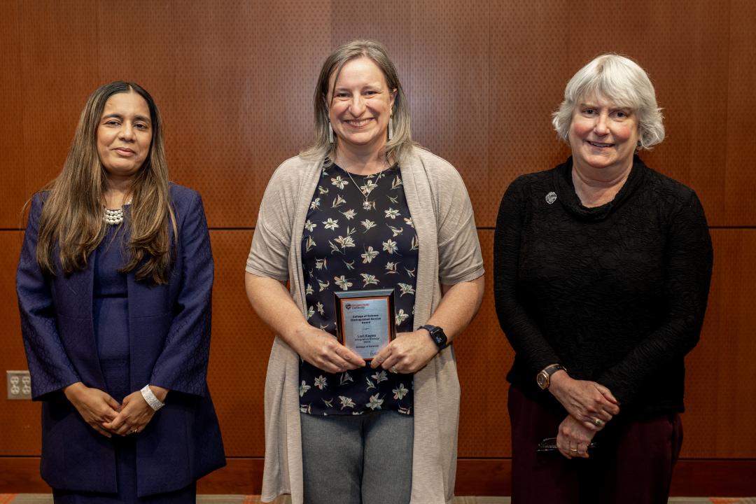 Lori Kayes accepts her award standing next to two other women. 