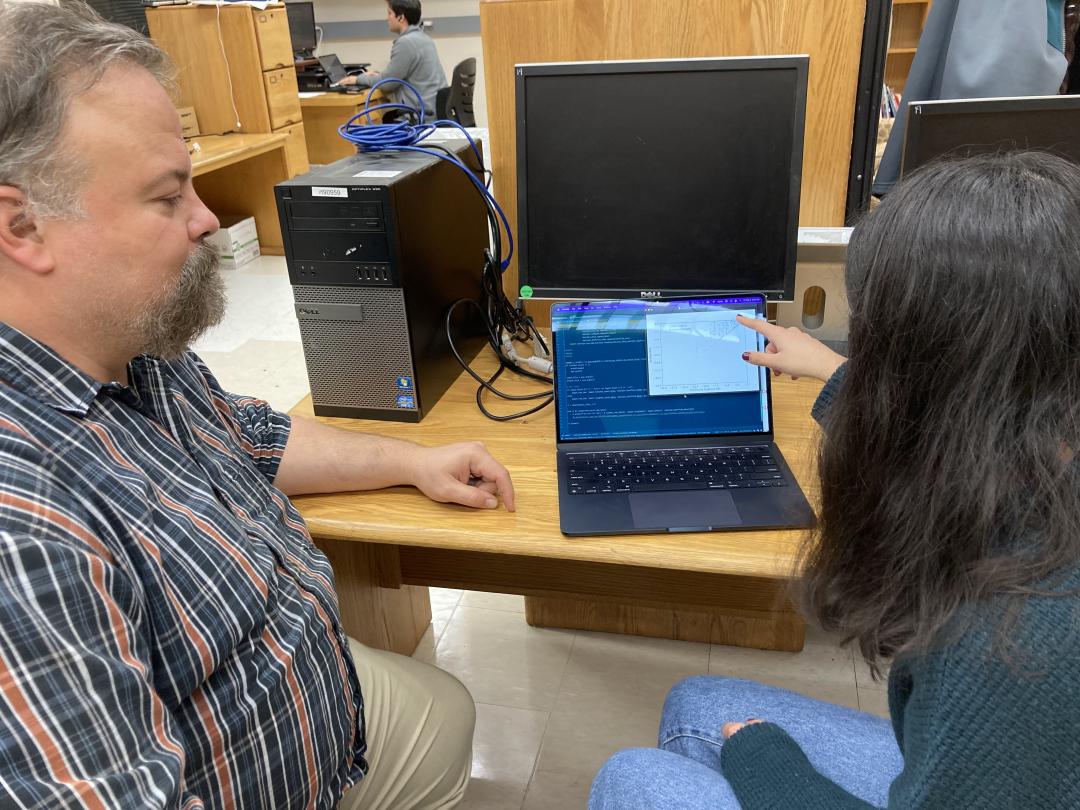 Alyssa Pratt points to a computer screen sitting at a desk next to Dave Hendrix.