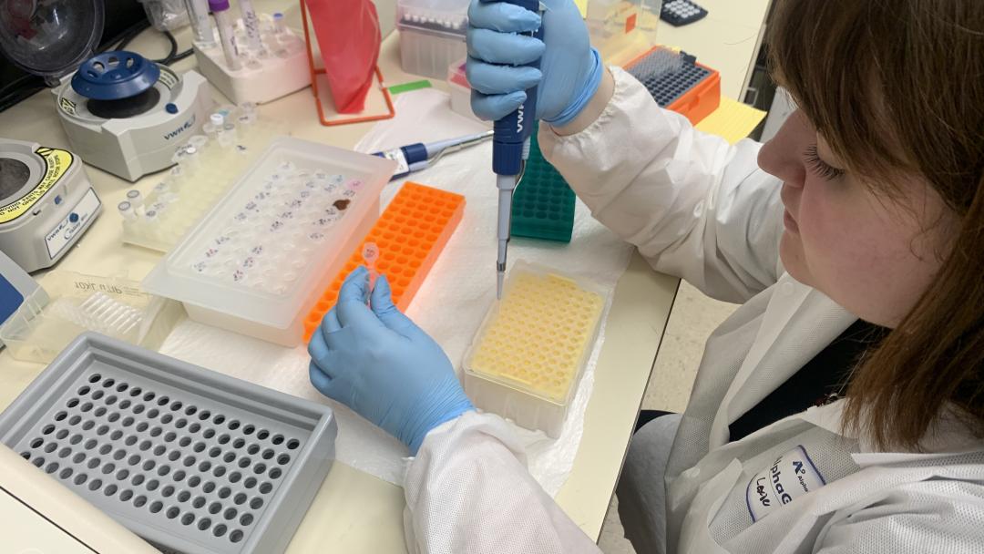 A scientist in a lab coat uses a pipet.