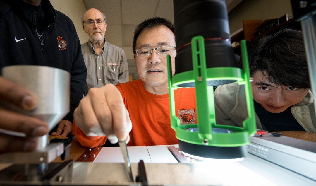 Four people stand in front of a microscope.