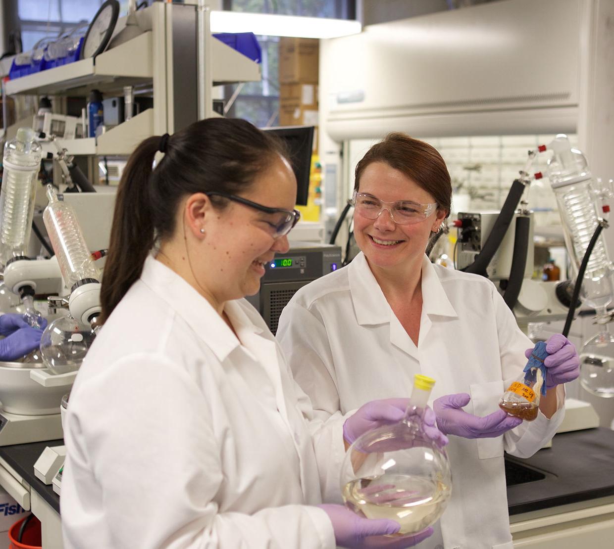 Sandra Loesgen with Cassandra Lew holding beakers in their lab