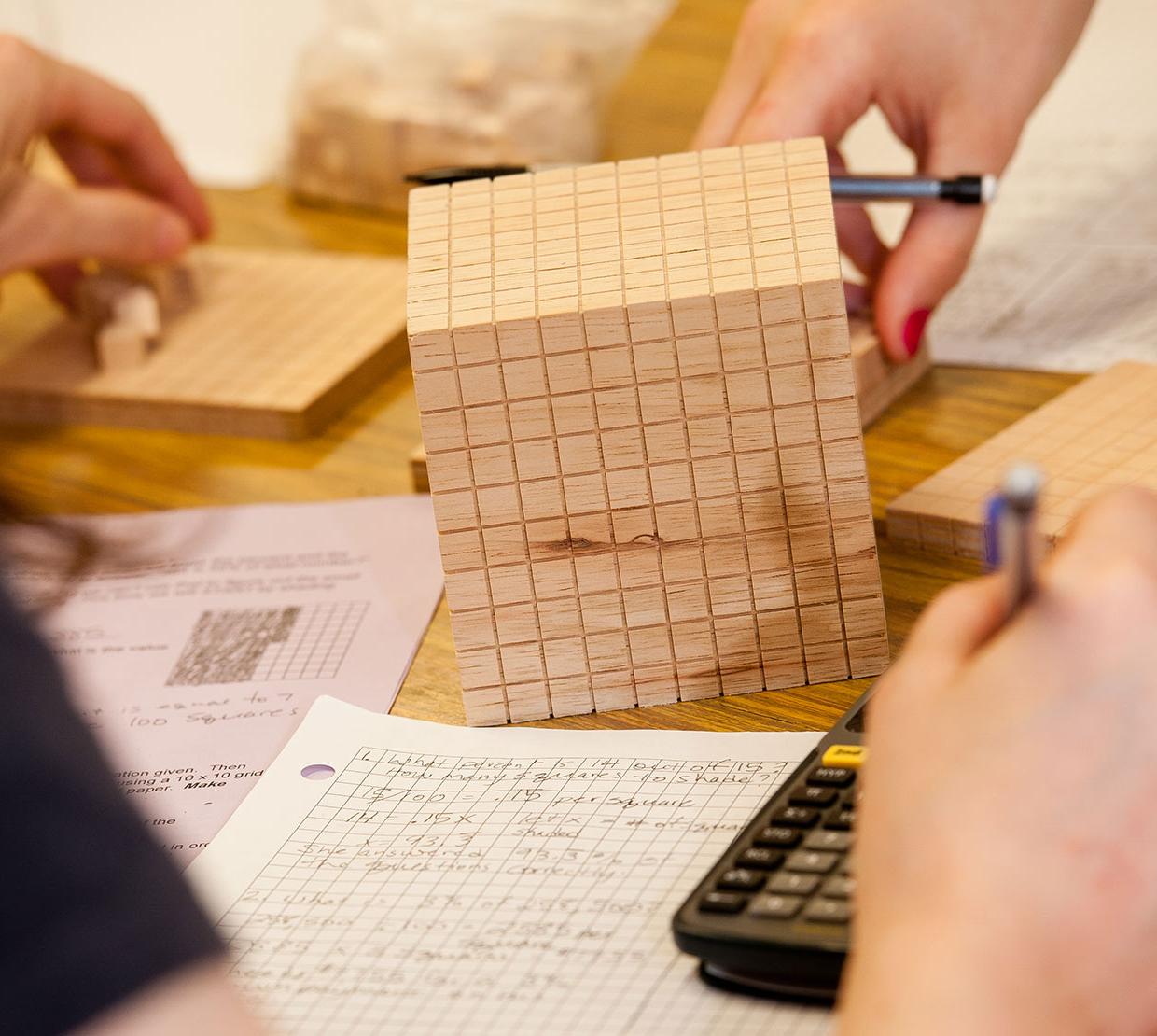 wooden cube on a table with math homework