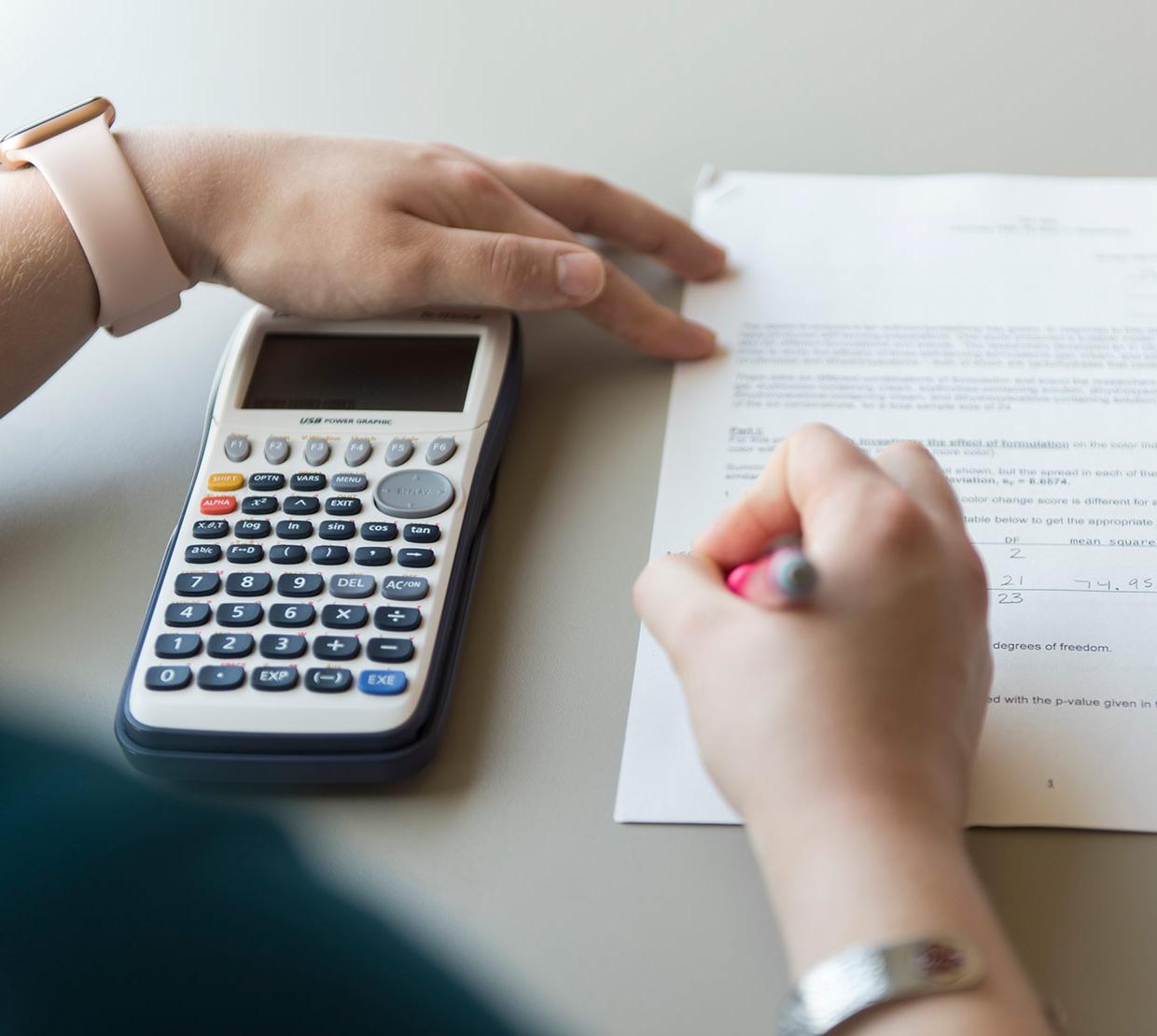 student working on math homework holding calculator