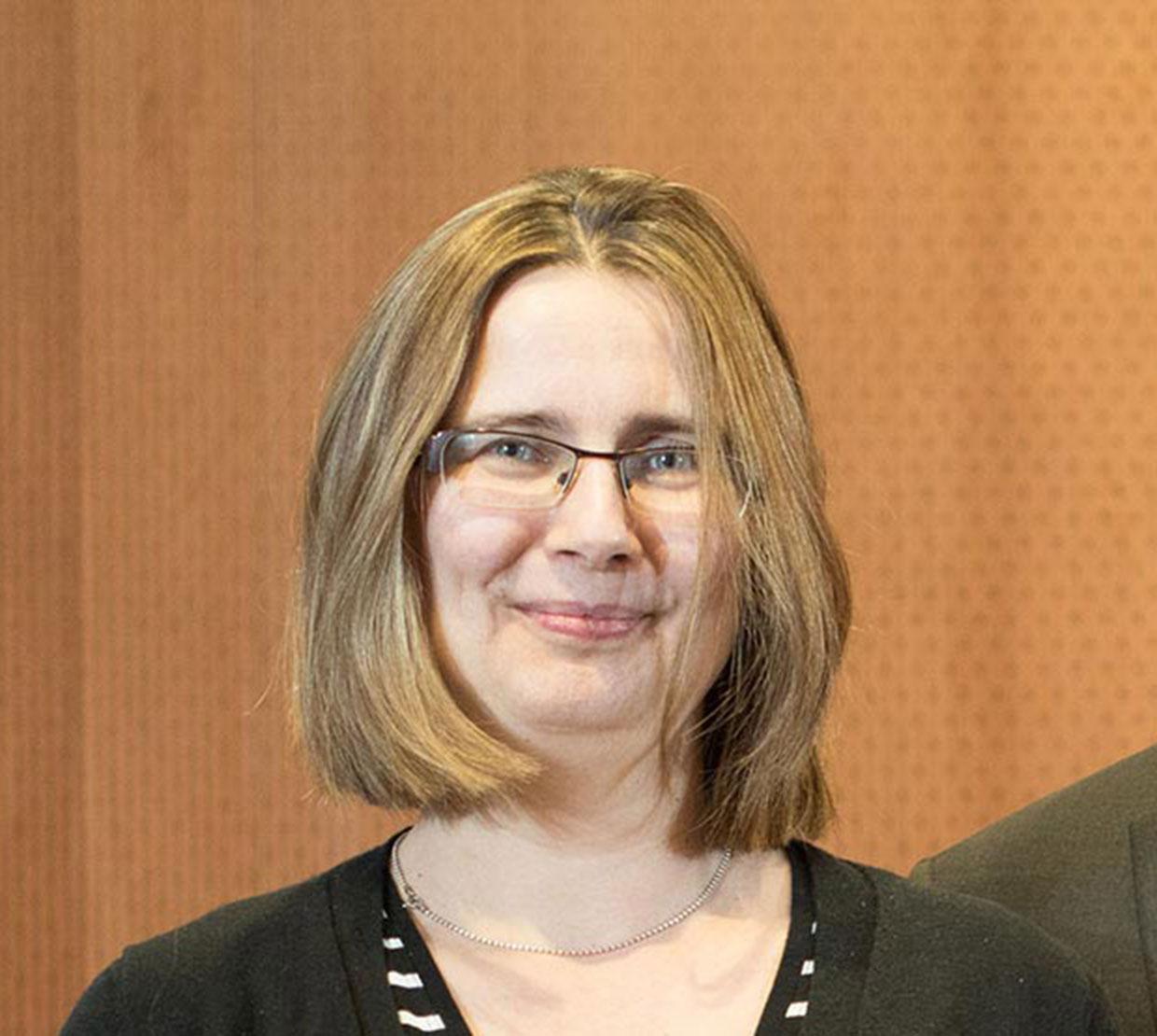 Oksana Ostroverkhova in front of wooden backdrop