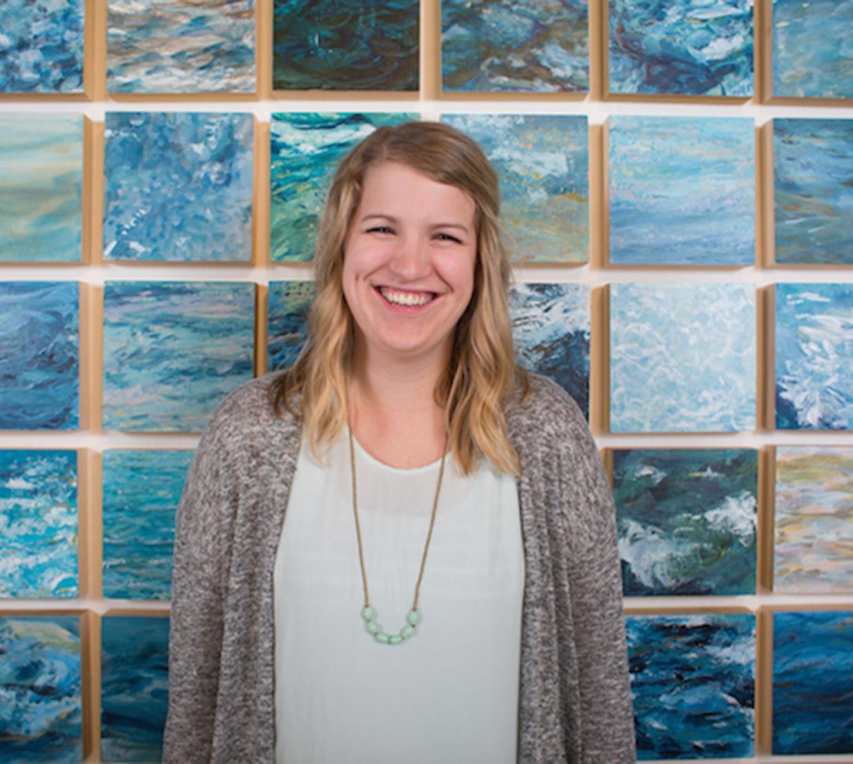 Abigail Losli standing in front of her paintings