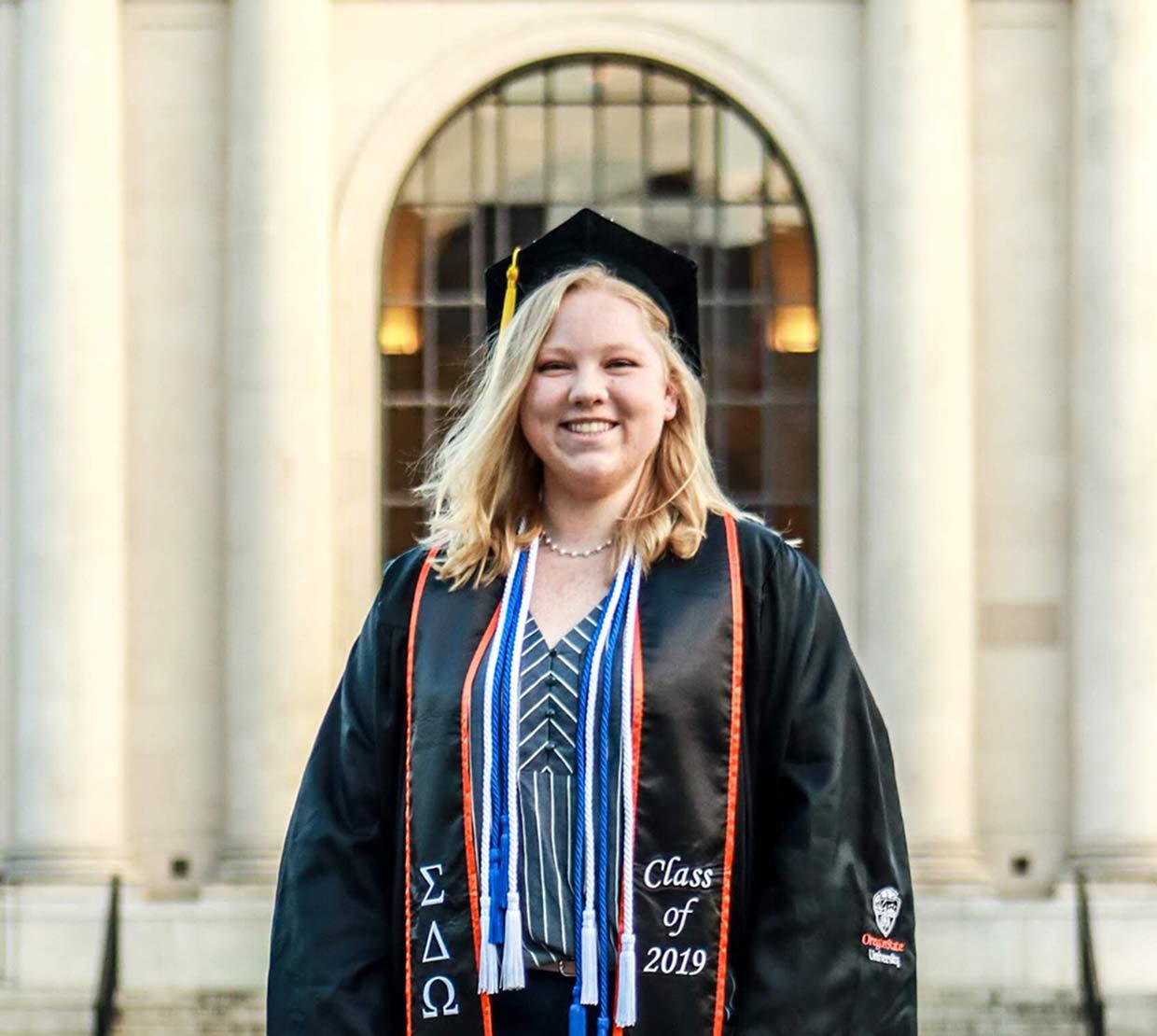 Ashley Victor wearing graduation gown in front of Memorial Union