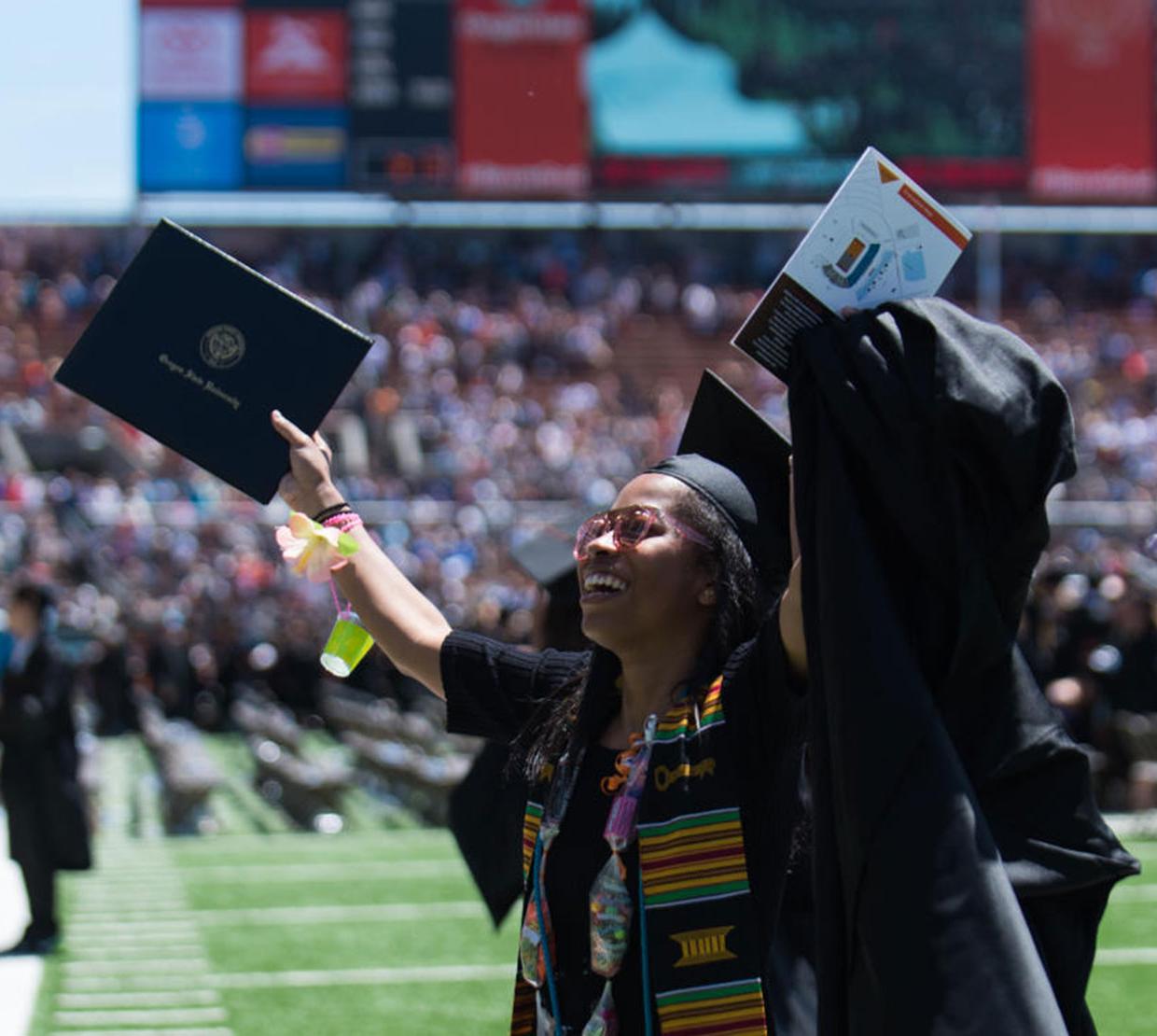 student holding up degree during graduation ceremony