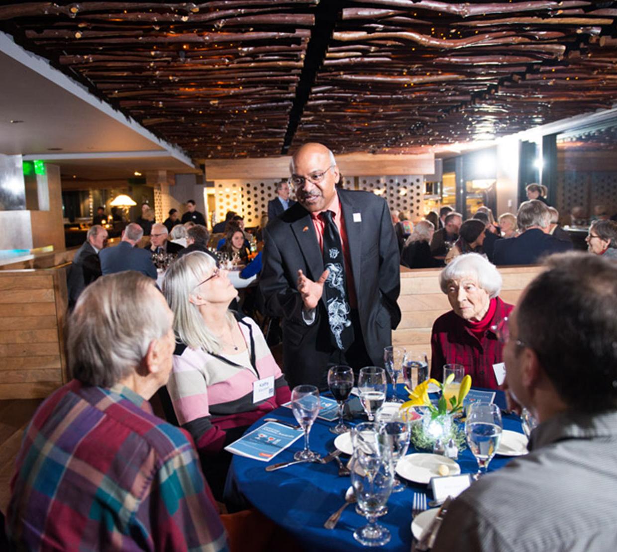Sastry talking to table of colleagues