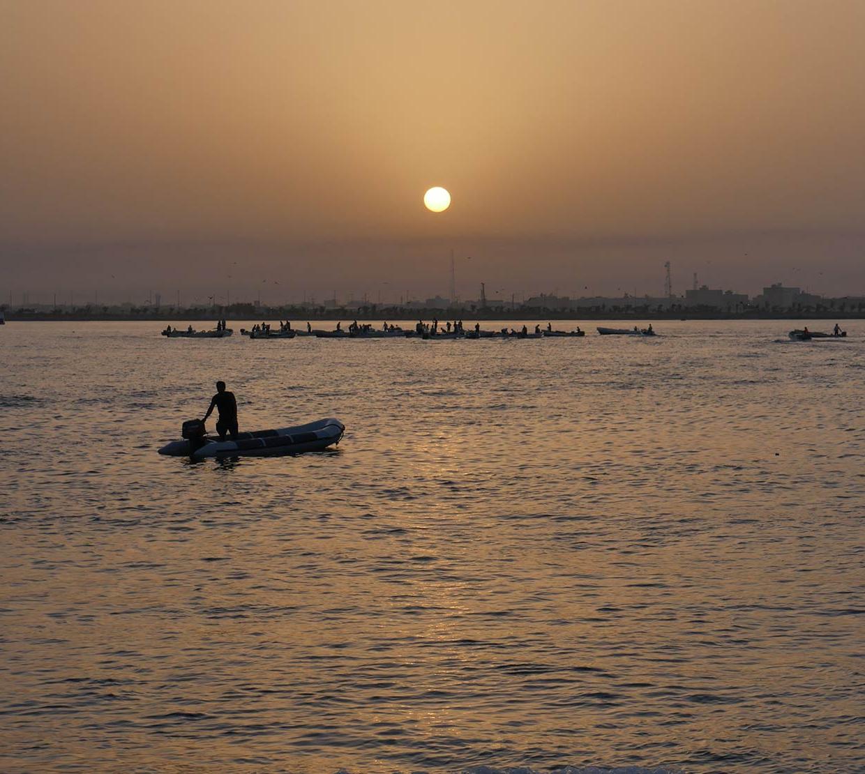 person riding small boat in ocean during sunset
