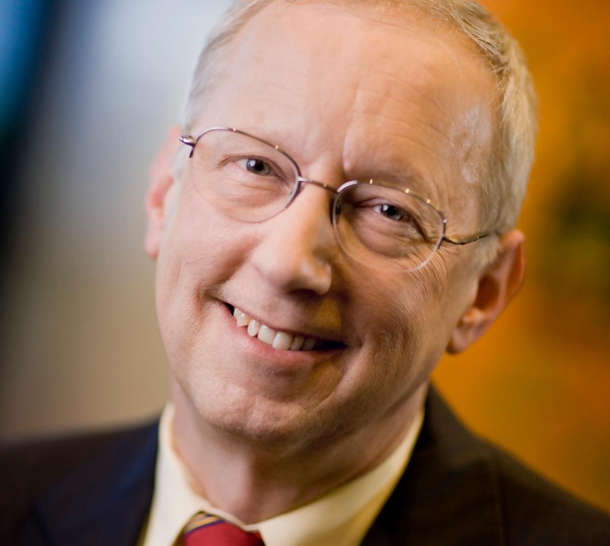 John Sall standing in front of painted, blurry backdrop