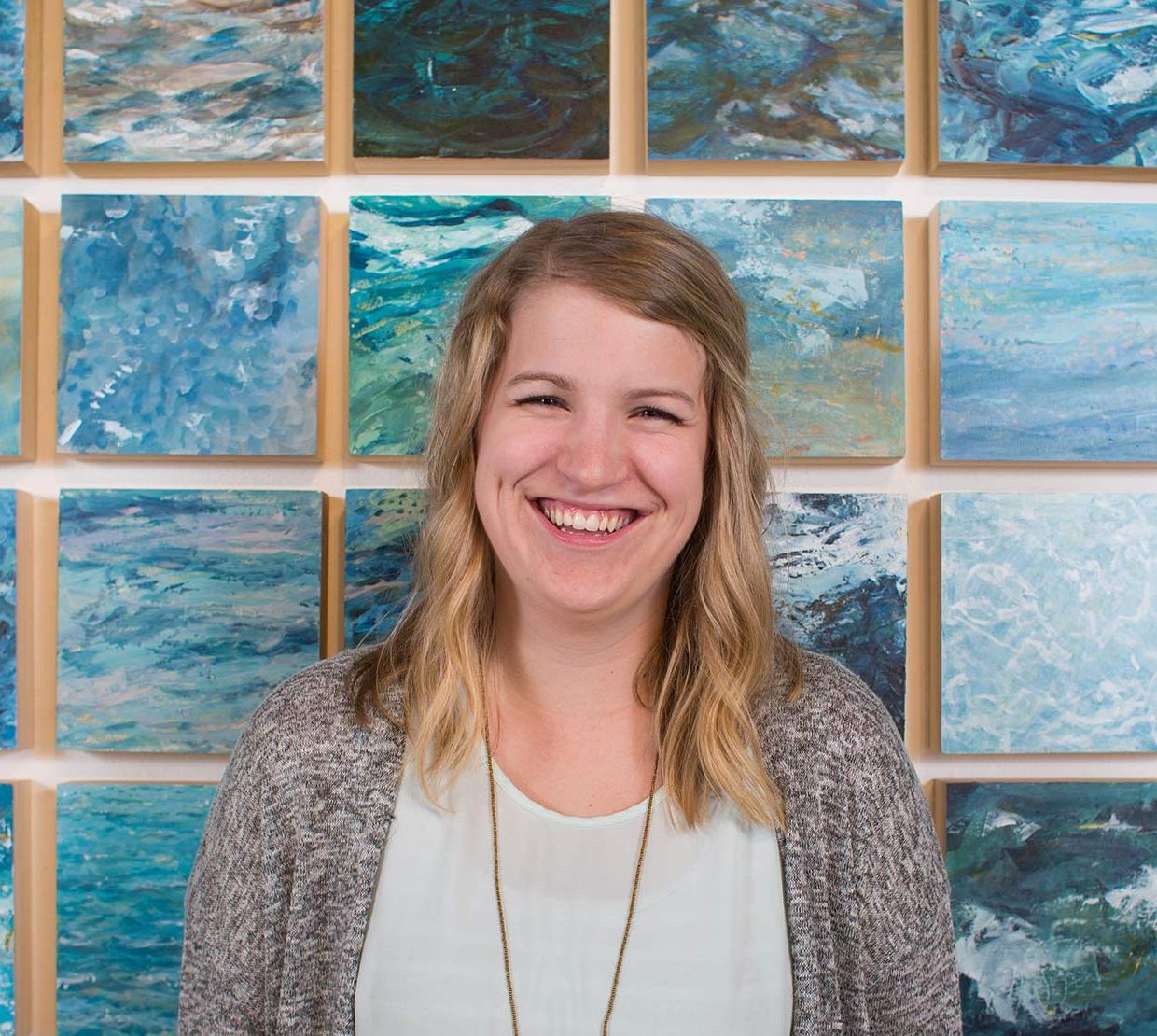 Abigail Losli standing in front of her paintings