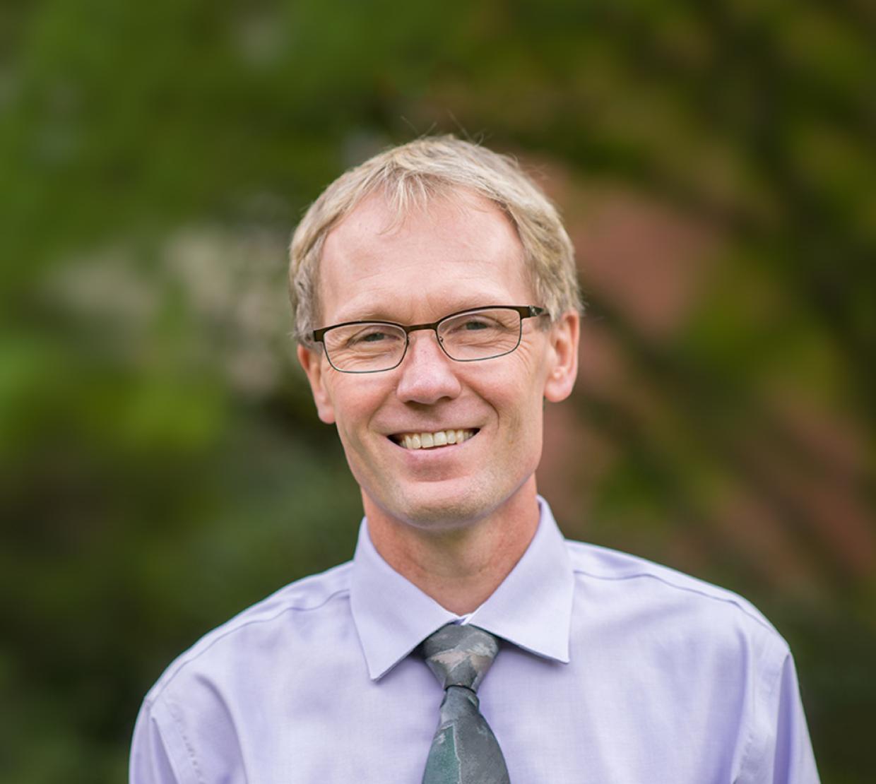 Roy Haggerty in front of shrubbery