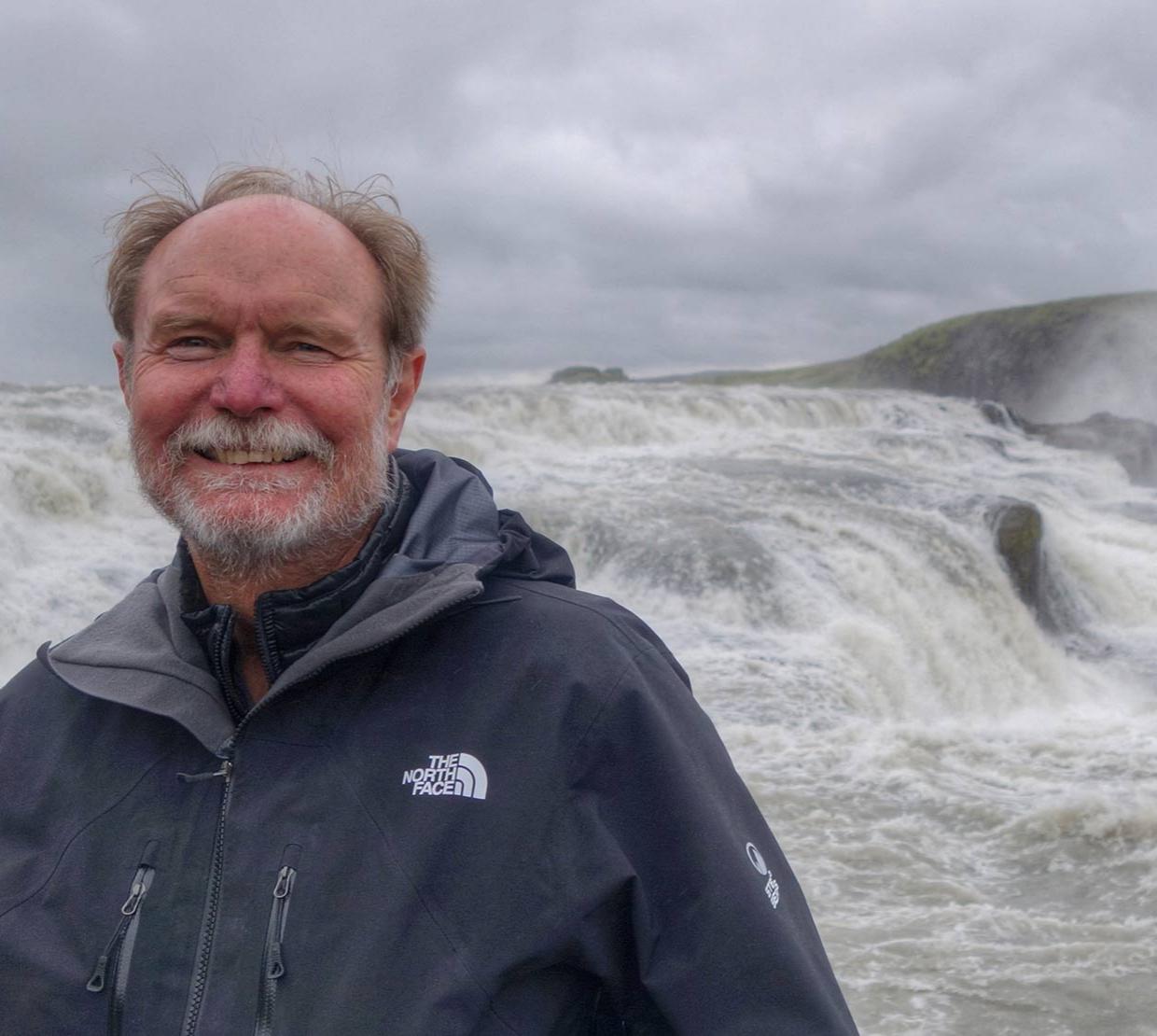 Joel Peterson standing in front of waterfall