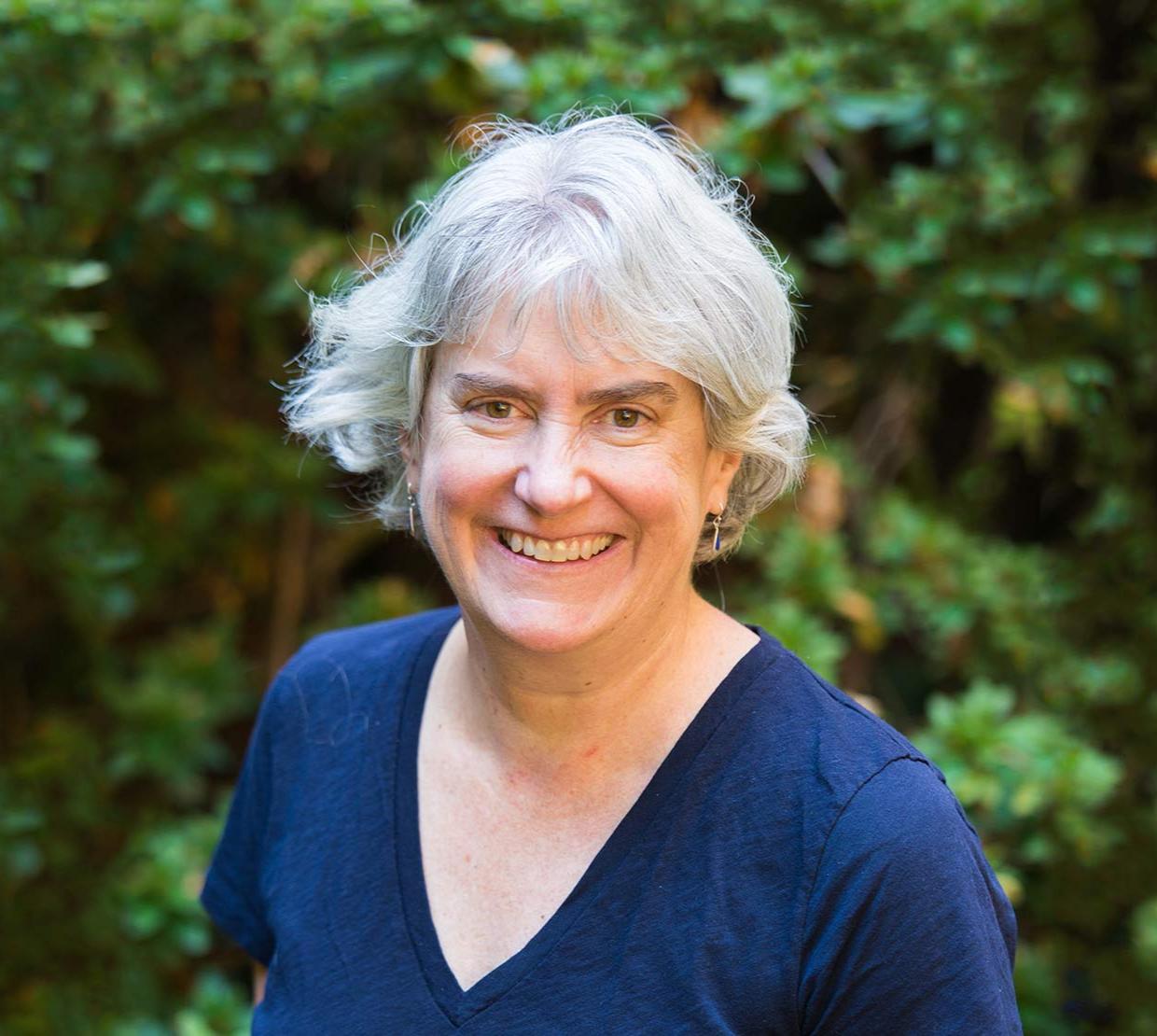 Virginia Weis in front of shrubbery