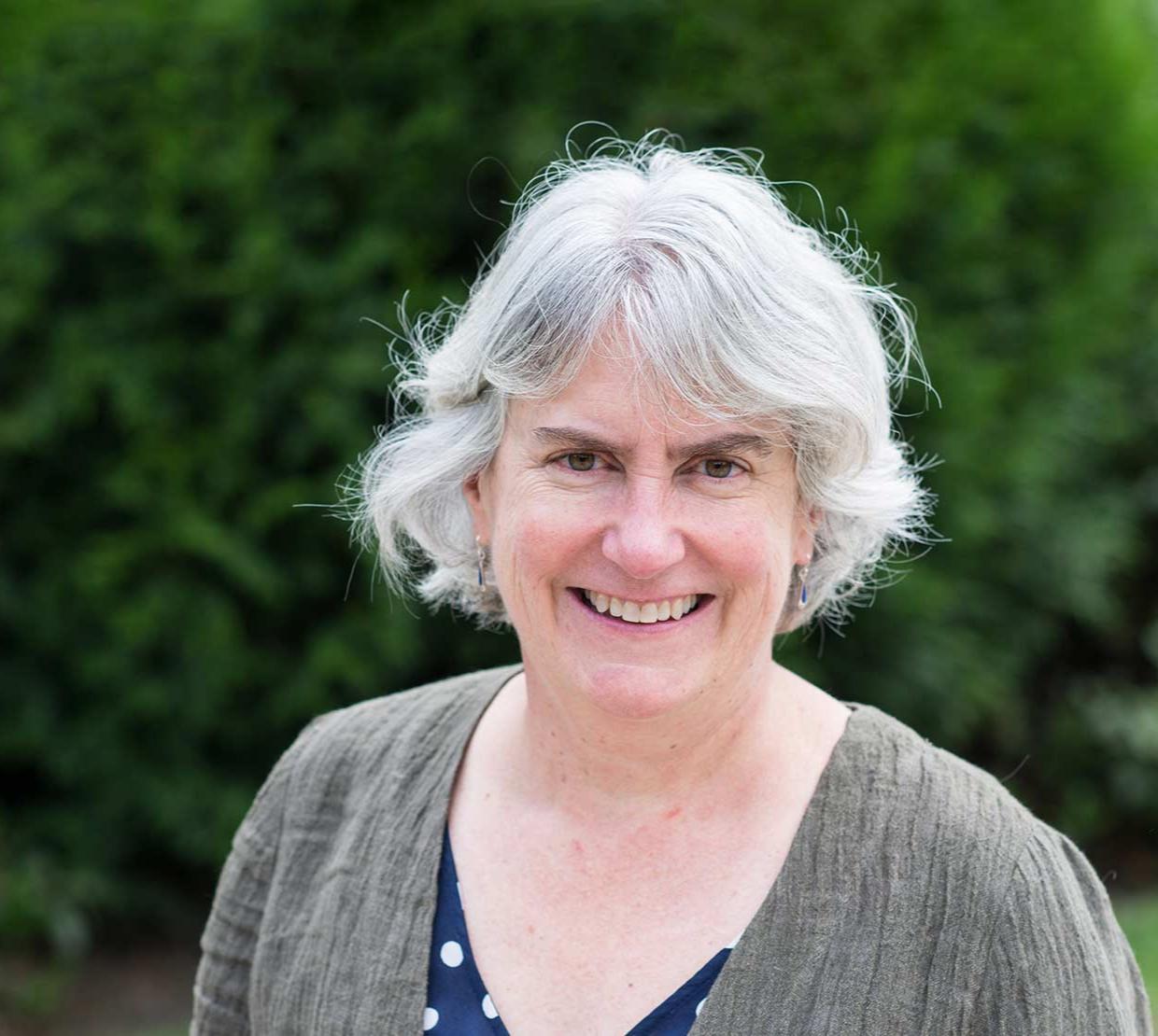 Virginia Weis in front of shrubbery