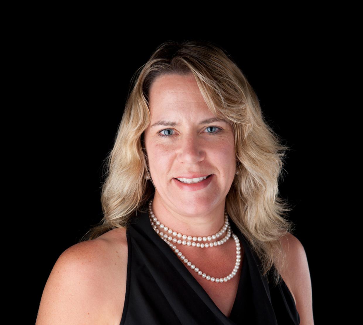 Staci Simonich standing in front of black backdrop