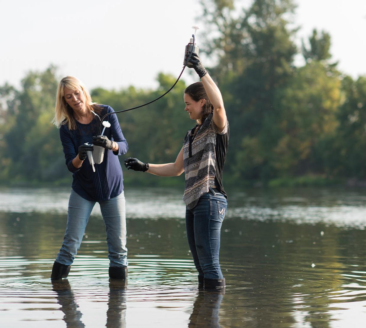 Kim Halsey and Cleo Davie-Martin collecting samples from a river.