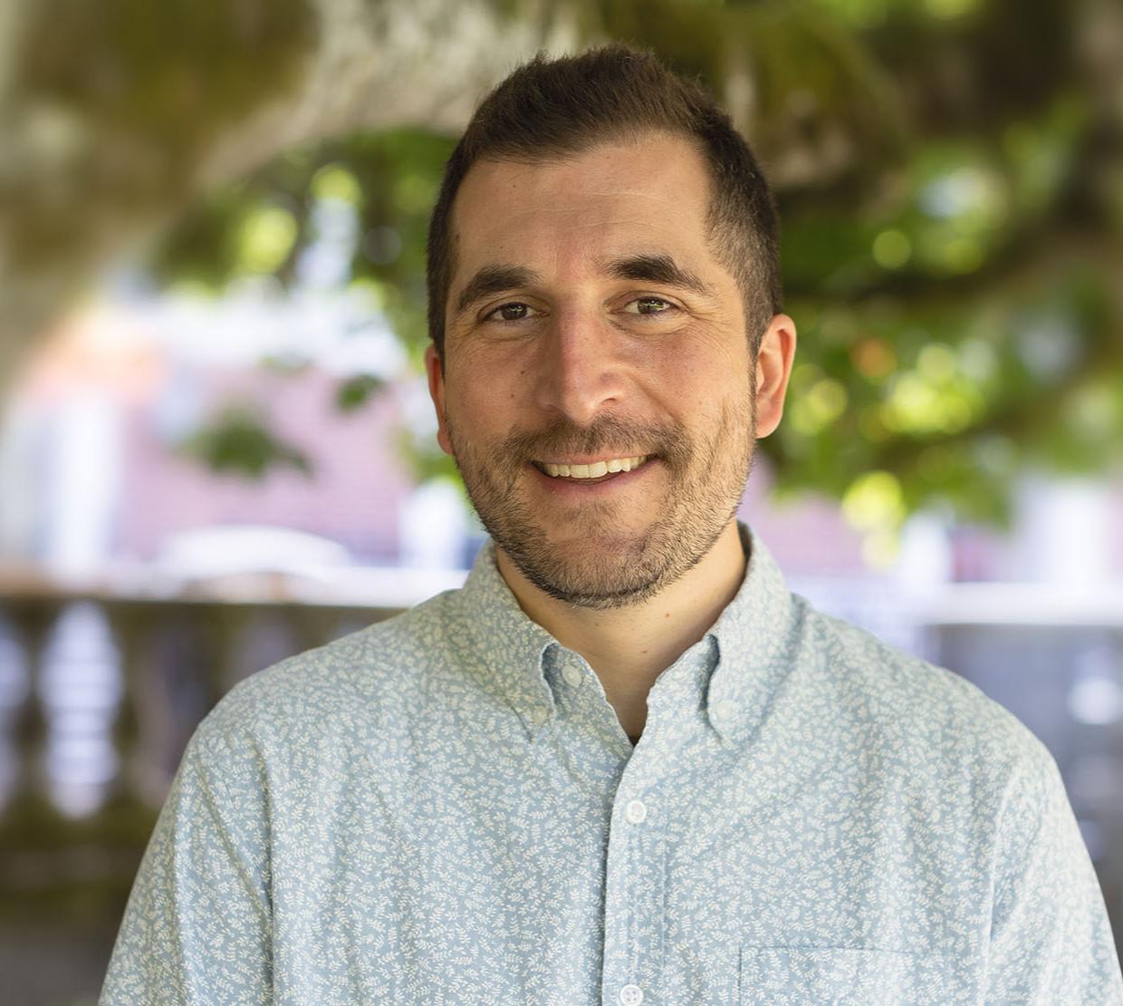 Headshot of Adam Chouinard in front of a tree.