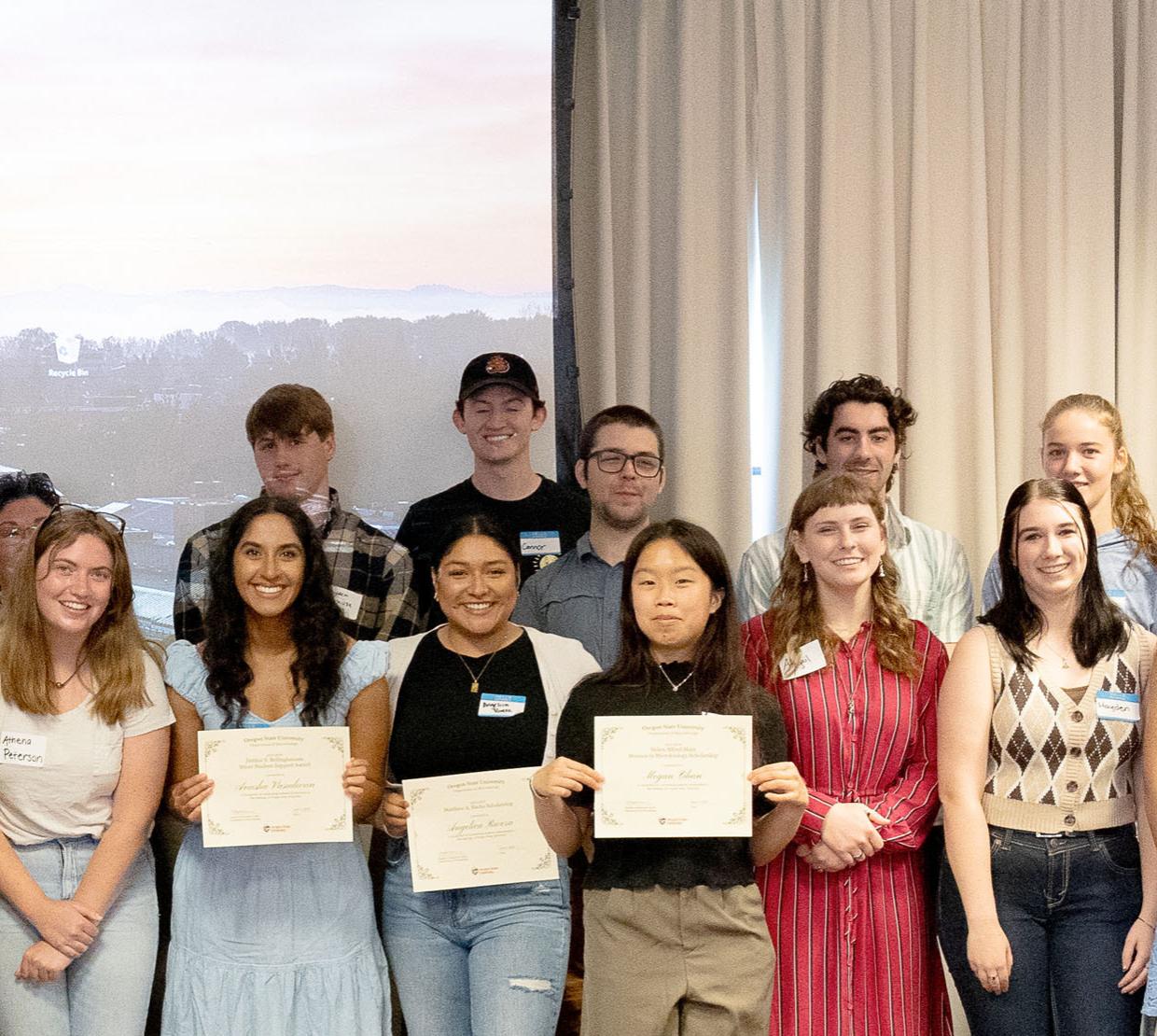 Smiling Oregon State recipients and donors celebrating and showing off their award certificates during a luncheon.