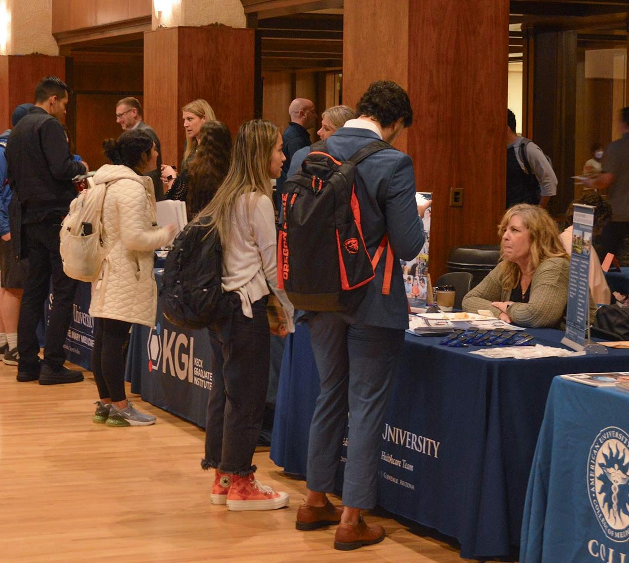 Wide shot of the Health Professions Fair, showing many universities meeting with students