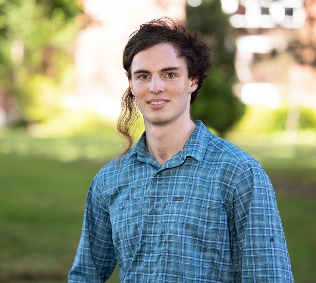 A headshot of a man smiling in a blue button-up.