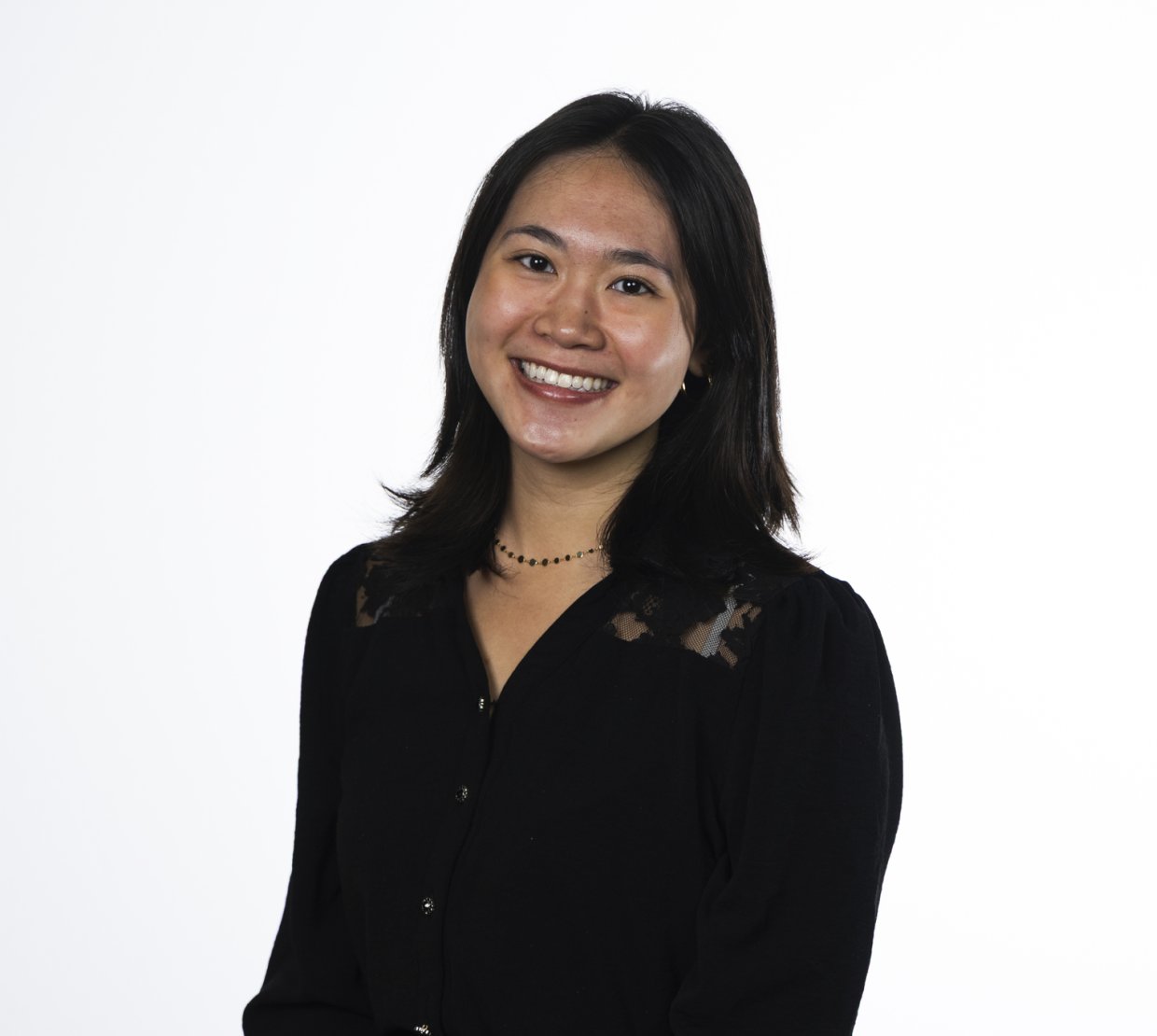 A woman in a black shirt poses for a headshot in front of a white background.