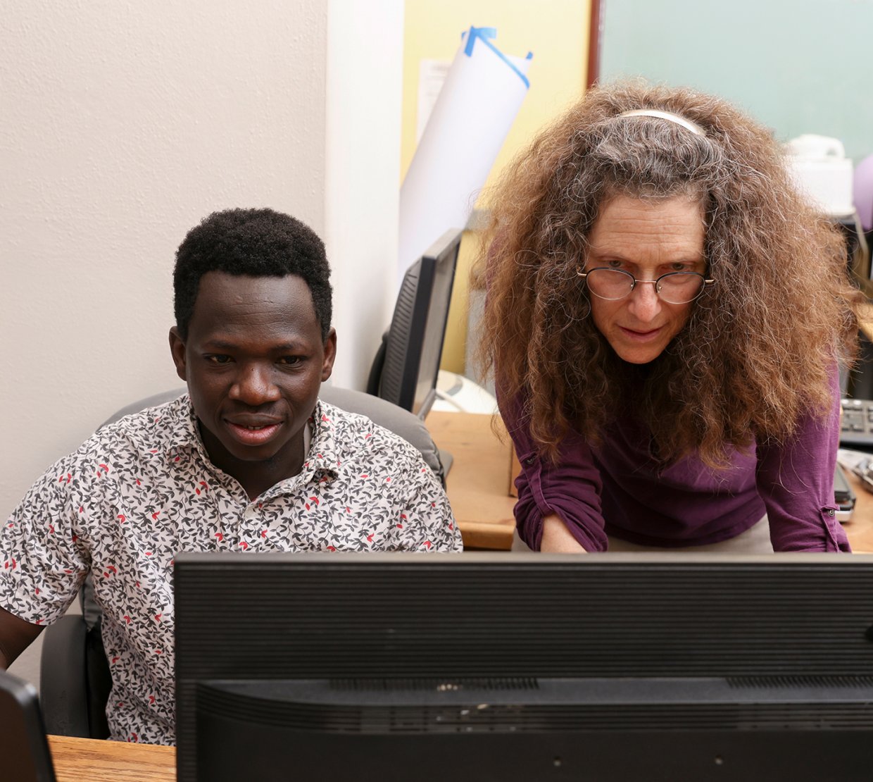 A professor and graduate student focus intensely on a computer screen as they work together.