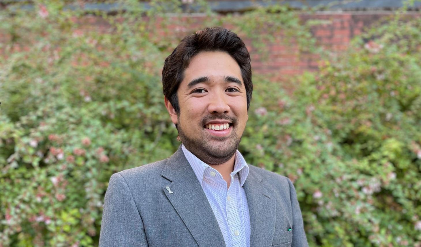 Kameron Kadooka standing in front of shrubbery.