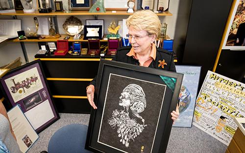 Jane Lubchenco holds up a portrait created by gyotaku artist Dwight Hwang using various marine species to apply the paint in addition to Lubchenco's own face.