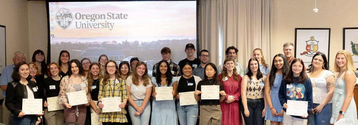 Smiling Oregon State recipients and donors celebrating and showing off their award certificates during a luncheon.