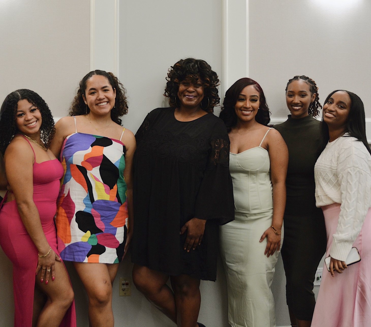 A smiling group of women in colorful formal wear