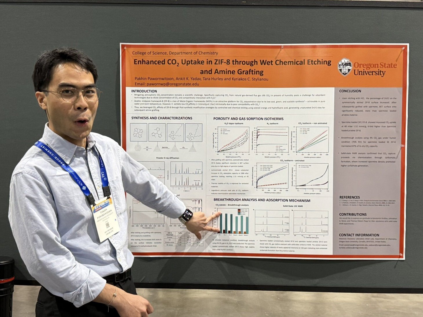 A grad student poses next to their research paper at the 2025 American Chemistry Society national conference. He is pointing and making an O shape with his mouth.