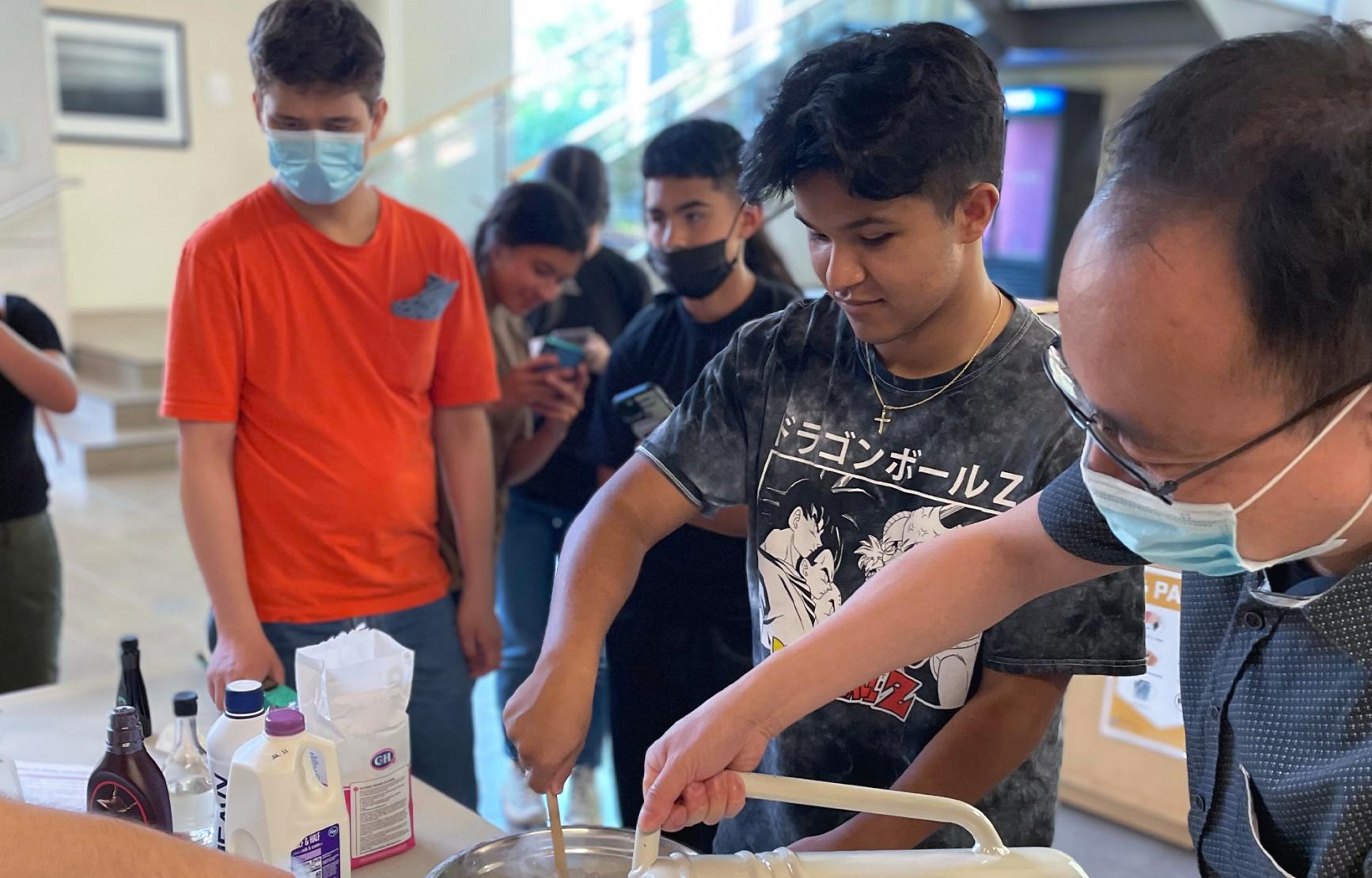 Chong Fang helps Juntos Program participants with a chemistry experiment.