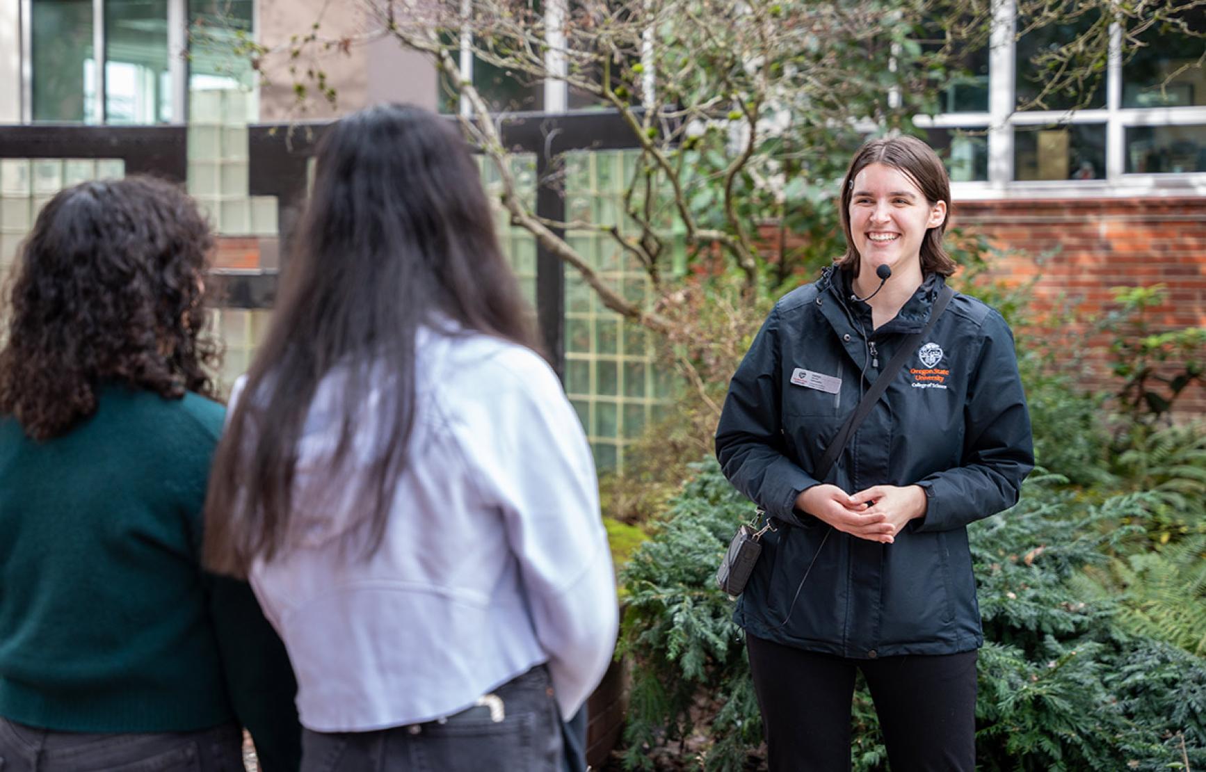 Ambassador Kaitlyn smiles as she shows two students the campus