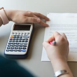 student working on math homework holding calculator