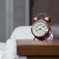 clock sitting on nightstand next to bed