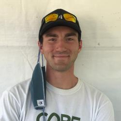 Zack Bango smiling in front of a white background, wearing a CORE shirt