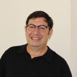 Juan Restrepo sitting in front of beige backdrop