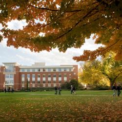 The Valley Library is seen with fall leaves on the ground and students walking across campus.
