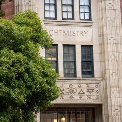 A brick building with the word "chemistry" stands behind a green tree.