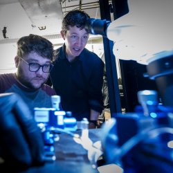 A professor shows a student how to use a piece of lab technology.