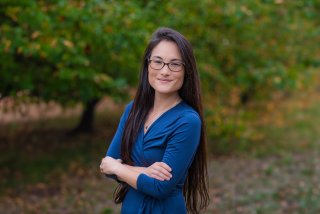 Smalley smiles at the company in front of green trees.