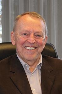 Headshot of white male smiling in front of curtains