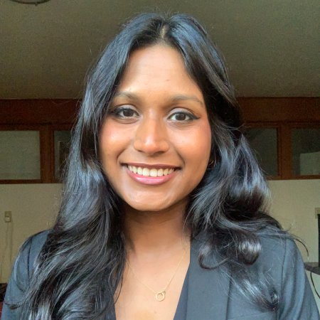 A smiling headshot of Sanjana Curtis in a blazer