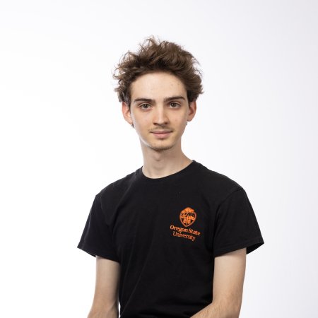 A man in a black shirt stands in front of a white background.