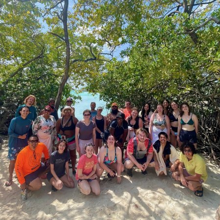 A group of people pose for a photo on a beach.